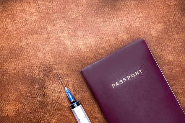 passaporte com seringa para vírus de vacinação em parede de couro marrom com conceito de espaço de cópia