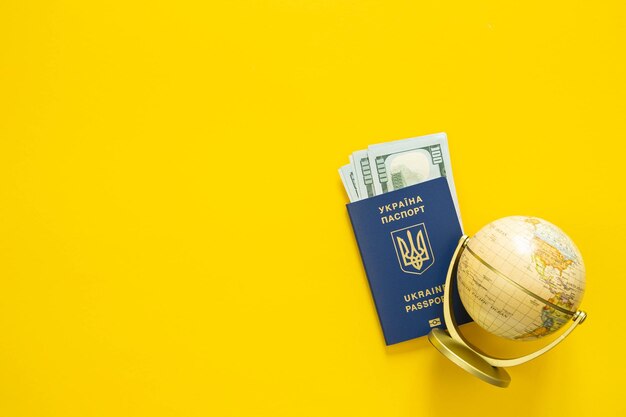 Passaporte de um cidadão da Ucrânia dinheiro e globo em fundo amarelo