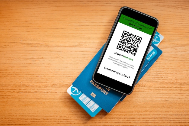 Passaporte e smartphone com digital do certificado de vacinação contra a doença de Covid-19.