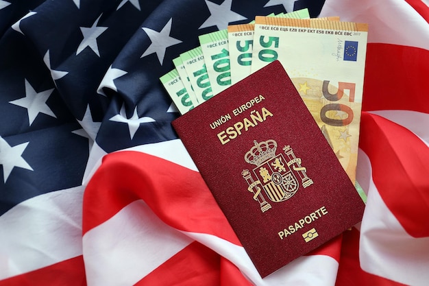 Passaporte espanhol vermelho da União Europeia e dinheiro em fundo da bandeira nacional dos Estados Unidos