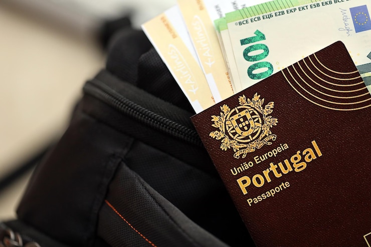 Foto passaporte português vermelho da união europeia com dinheiro e bilhetes de avião numa mochila turística