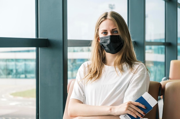 Passaporte ucraniano biométrico nas mãos da mulher olhando para a câmera sentada no aeroporto cidadão do ukr