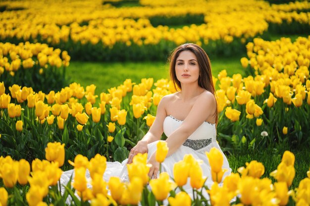 Passar o tempo livre ao ar livre Adolescente sorridente sentado no parapeito perto do espaço livre do jardim de tulipas