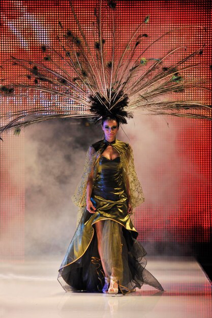 passarela de desfile de moda com bela jovem em vestido elegante e luxuoso com decoração de penas de pavão de pássaro