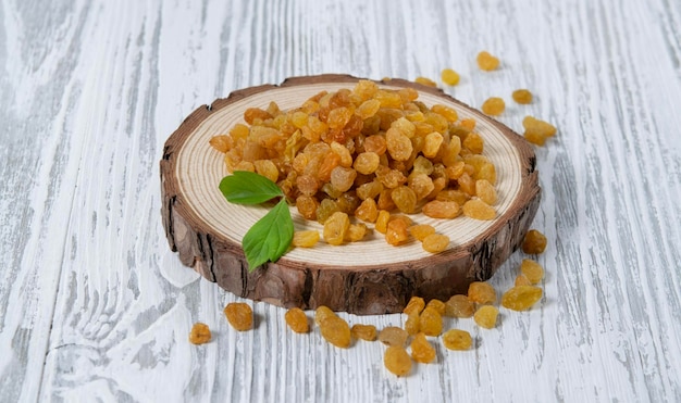 Passas de frutas secas em uma placa de madeira em um fundo branco de madeira Estilo rústico O conceito de lanches vegetarianos e dietéticos