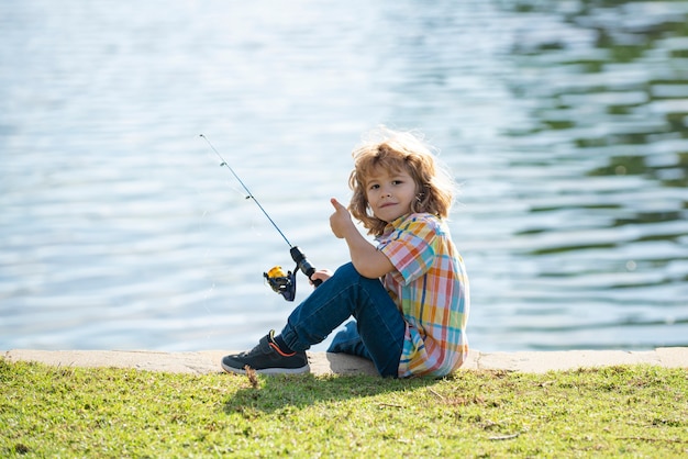 Passatempo infantil. Pesca infantil no lago. Menino com spinner no rio. Garoto no cais com vara.