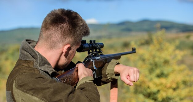 Passatempo masculino brutal Homem mirando fundo da natureza do alvo Habilidades de mira Caçador segura rifle mirando no meu alvo Caçador barbudo passa caça de lazer Equipamento óptico de caça para profissionais