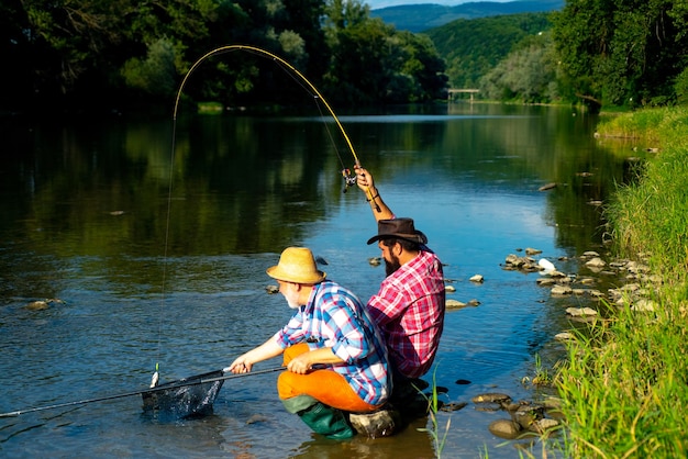 Passatempo masculino pescando dois amigos do sexo masculino vestidos com camisas pescando junto com rede e vara durante o m