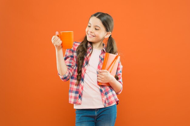 Passe um bom tempo com o livro favorito Garota segure a xícara de chá e livro Literatura para crianças Aproveite o tempo em casa Cacau quente e bom livro Combinação perfeita para uma noite aconchegante Lendo a lista de desejos