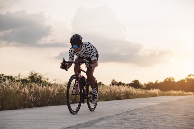 Passeio asiático do homem uma bicicleta no jogo do sol A imagem do ciclista no movimento no fundo