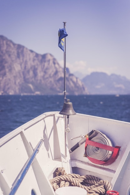 Passeio de barco Vista da proa do barco sobre a água azul celeste e a cordilheira Lago di Garda Itália