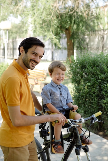 Passeio de bicicleta do pai e do filho na cadeira de bebê