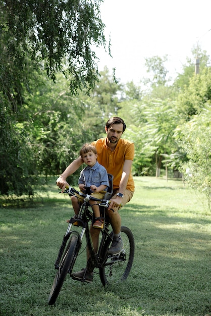 Passeio de bicicleta do pai e do filho na cadeira de bebê