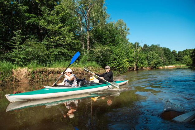 Passeio de caiaque em família Um casal de idosos remando um barco no rio uma caminhada na água uma aventura de verão Esportes relacionados à idade juventude mental e turismo de saúde velhice ativa