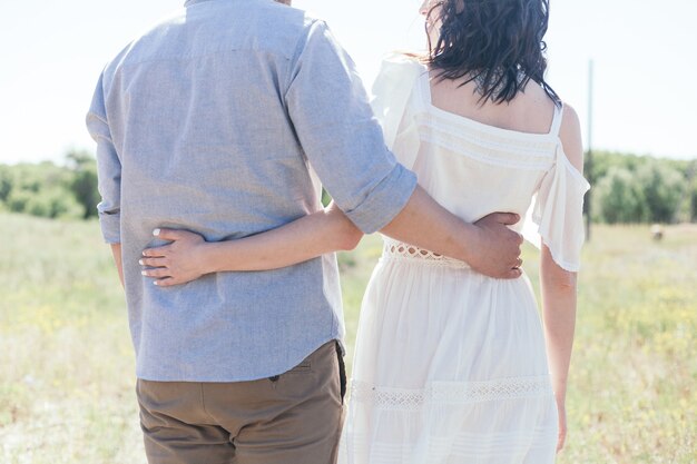 Passeio de casamento na floresta de pinheiros. Dia ensolarado. Casal de noivos na floresta. Linda noiva e noivo em uma caminhada. Vestido de noiva branco. Bouquet de peônias e hortênsias.