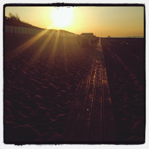 Passeio de madeira na praia de areia durante o pôr-do-sol