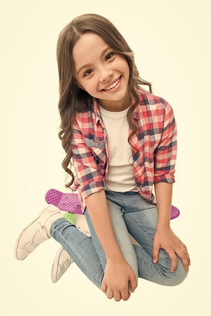 Passeio feliz Garota feliz senta-se na placa de um centavo Originalmente projetado como skate de meninas Passatempo adolescente moderno Garota rosto feliz sente-se na placa de um centavo fundo branco Aprendendo a andar de placa de centavo