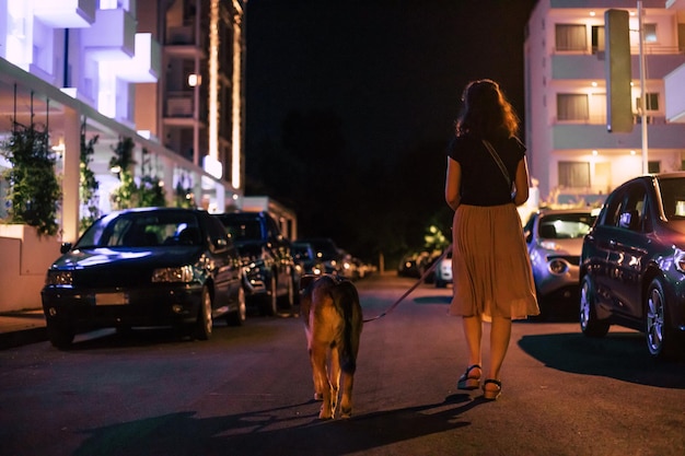 Passeio noturno com um animal de estimação Garota com vista traseira de cachorro grande