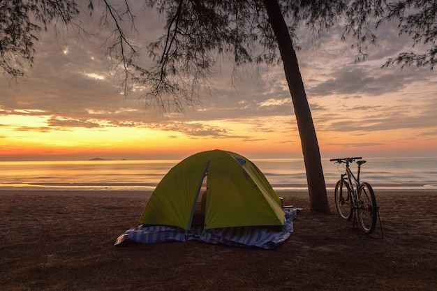 Passeios de bicicletas e tendas durante o nascer do sol na praia. bicicletas e barraca de abrigo na praia na costa do mar báltico