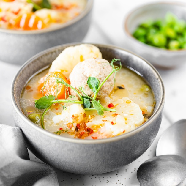 Passo 6 Receita de sopa com almôndegas couve-flor ervilhas cenouras e creme em um fundo branco Foco seletivo quadrado