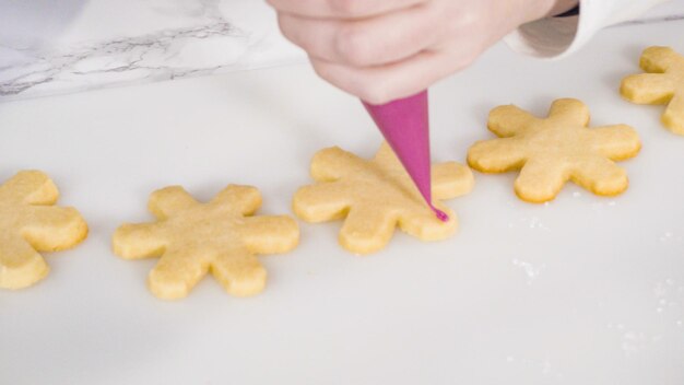 Passo a passo. Biscoitos de açúcar em forma de floco de neve com glacê real rosa.