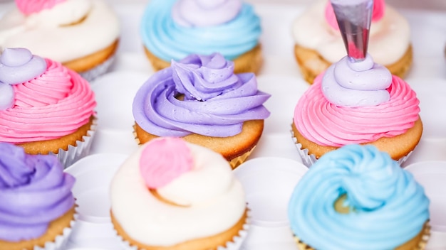 Passo a passo. Chef de pastelaria com cobertura de creme de manteiga em cupcakes de unicórnio para festa de aniversário de menina.