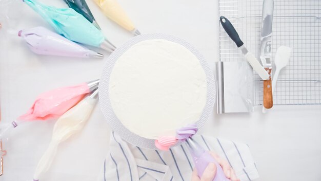 Passo a passo. Chef de pastelaria com cobertura de creme de manteiga no bolo de unicórnio para festa de aniversário de menina.