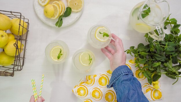 Passo a passo. Enfeitando a limonada fresca tradicional com fatias de limão e hortelã.