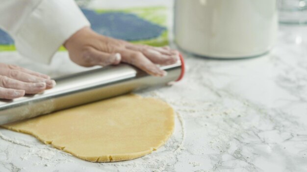 Passo a passo. Estender a massa com um rolo para assar biscoitos de açúcar de cata-vento vermelhos, brancos e azuis.