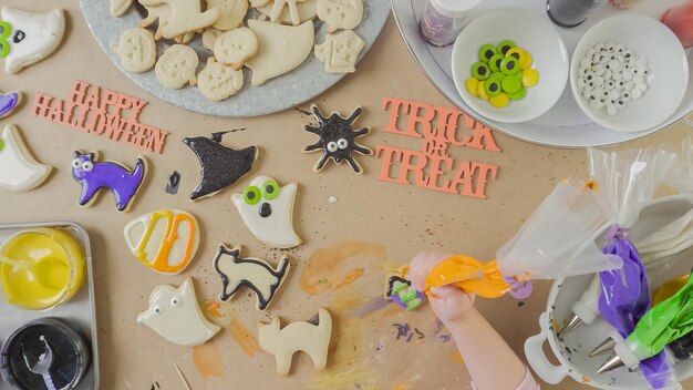 Passo a passo. Mãe e filha decorando biscoitos de açúcar de Halloween com crosta de gelo real colorida.