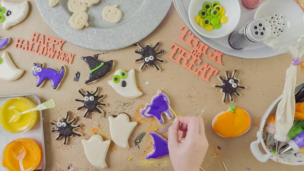 Passo a passo. Mãe e filha decorando biscoitos de açúcar de Halloween com crosta de gelo real colorida.