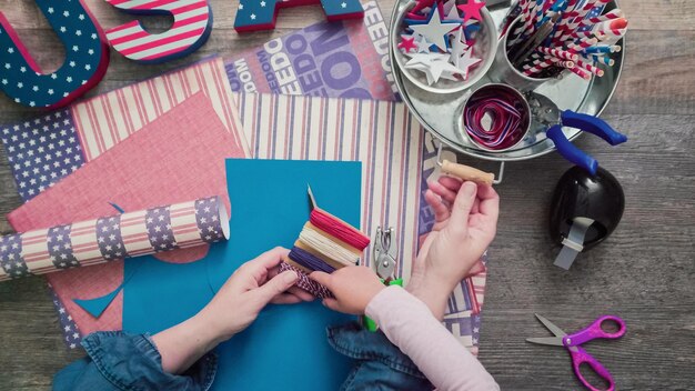 Passo a passo. Mãe e filha fazendo bombinhas de papel para a celebração de 4 de julho.