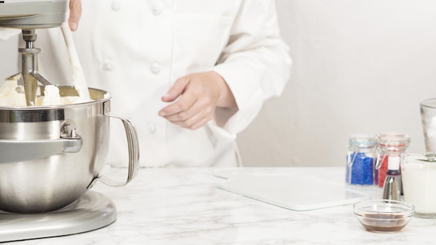 Passo a passo. Misturar os ingredientes na batedeira de cozinha em pé para fazer a cobertura de creme de manteiga.