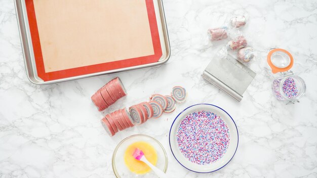 Passo a passo. Postura plana. Cortar a massa com uma faca de massa para assar biscoitos de açúcar de cata-vento vermelho, branco e azul.