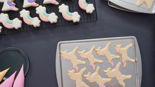 Passo a passo. Postura plana. Decorando biscoitos de açúcar de unicórnio com glacê real na assadeira.