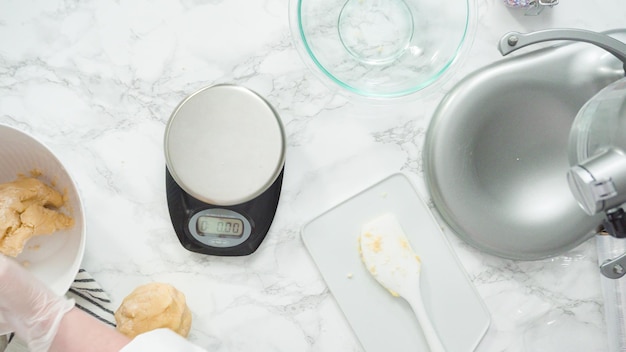 Passo a passo. Postura plana. Medindo a massa de biscoito com uma balança de cozinha digital para assar biscoitos de açúcar de cata-vento vermelhos, brancos e azuis.