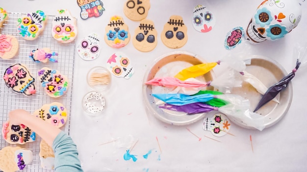 Passo a passo. Postura plana. Menina decorando biscoitos de caveira de açúcar com glacê real para o feriado de Dia de los Muertos.