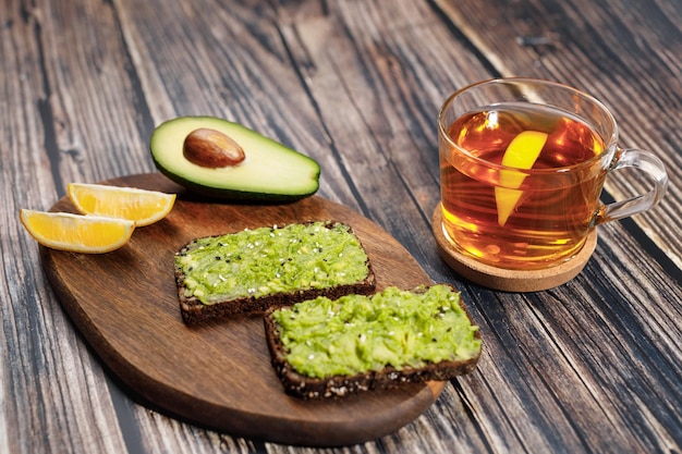 Pasta de aguacate untada en pan de centeno Cerca de rodajas de limón y medio aguacate Tostada de guacamole