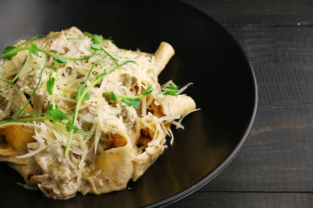 Pasta Alfredo con beaf, chease y microgreen closeup sobre mesa de madera.