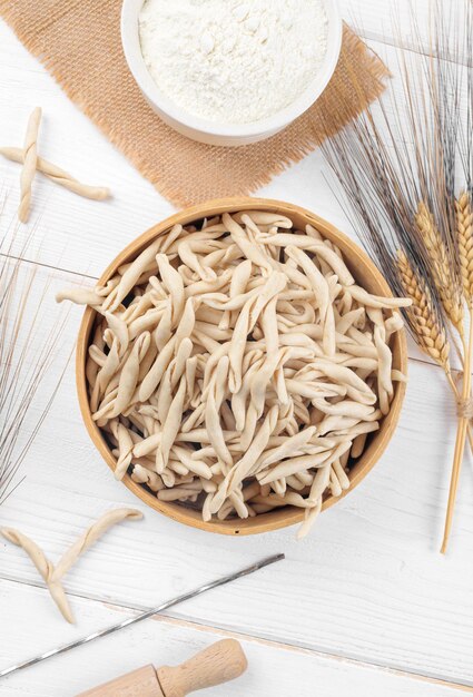 Pasta apuliana cruda de trigo integral llamada Pizzarieddi o maccaruni en un tamiz sobre una mesa de madera blanca