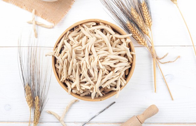 Pasta apuliana cruda de trigo integral llamada Pizzarieddi o maccaruni en un tamiz sobre una mesa de madera blanca