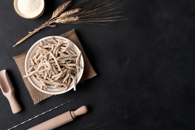 Pasta apuliana de trigo integral llamada Pizzarieddi o maccaruni sobre mesa negra. Fondo de pasta casera italiana