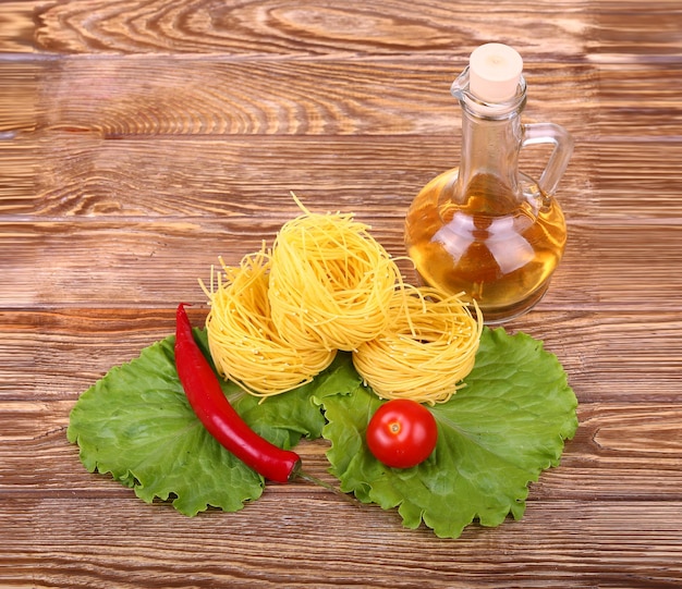 Pasta auf dem hölzernen Hintergrund mit Tomatensalat, Pfeffer, Olivenöl und Pfeffer