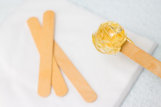 Pasta de azúcar o miel de cera para depilar con palitos de madera para encerar.