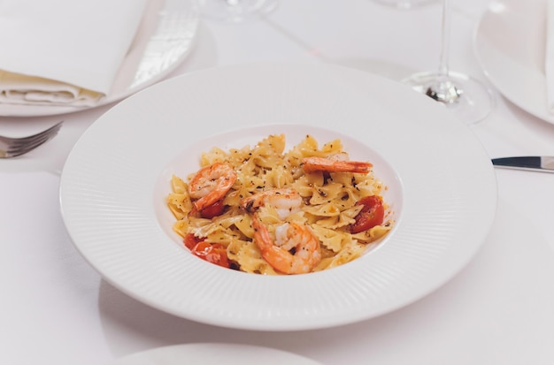 Pasta bavette com camarões fritos bechamel molho de menta folha de alho tomates chili em prato branco vista de cima cozinha italiana