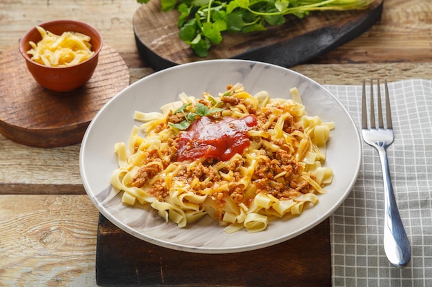 Pasta boloñesa adornada con verduras y queso en un plato sobre una mesa de madera sobre un soporte