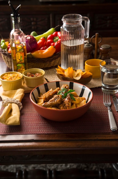 Pasta boloñesa con alitas de pollo Perú comida reconfortante tradicional peruana mise en place mesa de madera