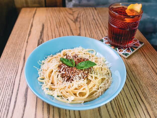 pasta boloñesa en el plato y cóctel a la antigua en la mesa del bar