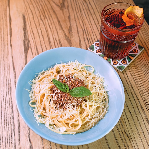 pasta boloñesa en el plato y cóctel a la antigua en la mesa del bar