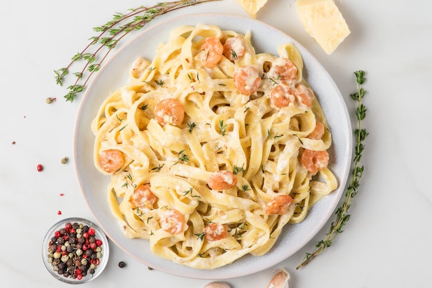 Pasta con camarones, salsa cremosa, queso parmesano y tomillo en un plato. Fettuccine mediterráneo con mariscos